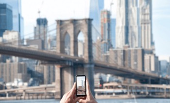 pessoa no celular vendo a ponte do Brooklyn exemplo de como ligar dos EUA para o Brasil