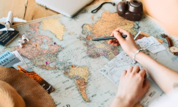 pessoa montando um roteiro de viagem no mapa com destinos internacionais